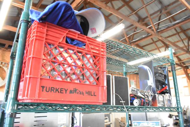 Two-tier shelf with Sony speakers, Star Wars Darth Vader doll, jerseys, and a red Turkey Hill crate containing items.