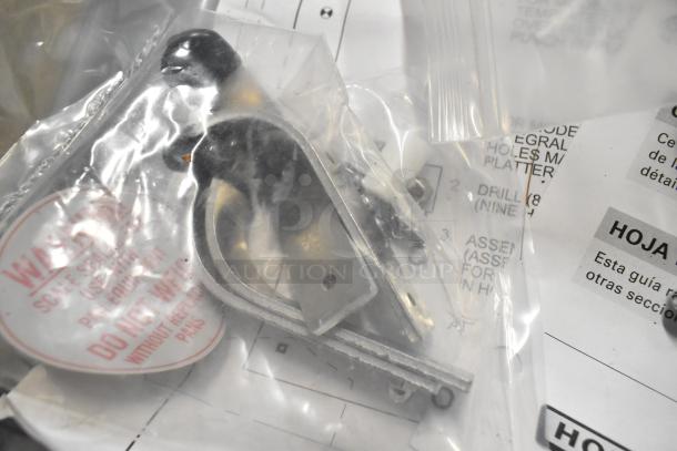 Bag of metal parts with warning label, possibly accessories for Hobart HWS-4C, against a background of technical documents.