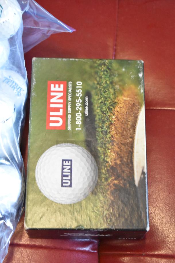Lot of various golf balls including TaylorMade and Callaway in a plastic Bag. Golf ball box marked "Uline" visible.
