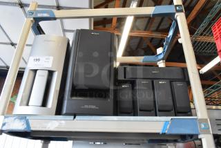 Sony speaker set, including various models, displayed on shelves. Features include black and silver finishes. Auction tag visible.