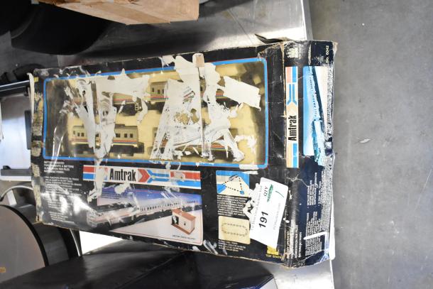 Amtrak 6042 Toy Train in original packaging. Box is damaged with peeling and tears, showing parts of the train inside.