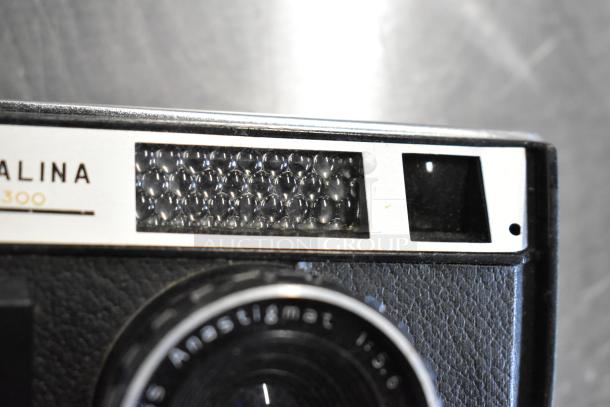 Halina 1:5.6 film camera with Anastigmat lens, vintage design, textured body; lens markings visible.