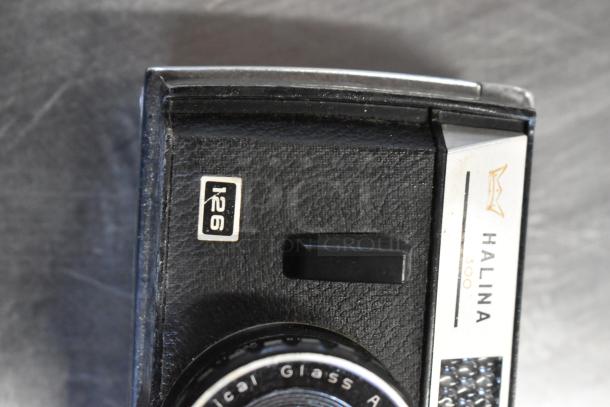 Halina 1:5.6 film camera with I-26 marking, black body, vintage design. Appears in used condition.
