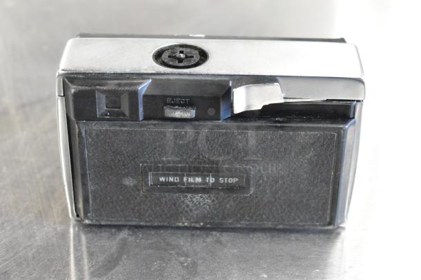 Halina 1:5.6 film camera with "Wind Film To Stop" label, showing moderate wear. Classic design, includes Honeywell Tilt-a-mite Gauge.