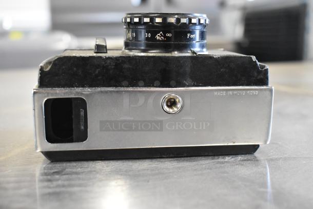 Halina 1:5.6 film camera in worn condition, featuring focus dial and "Made in Hong Kong" marking on metal base.