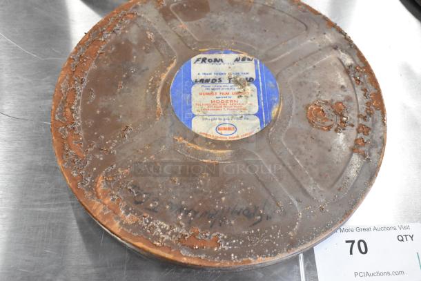 Rusted metal film reel case with "Humble Film Library" label and visible wear. Contains vintage film reels.