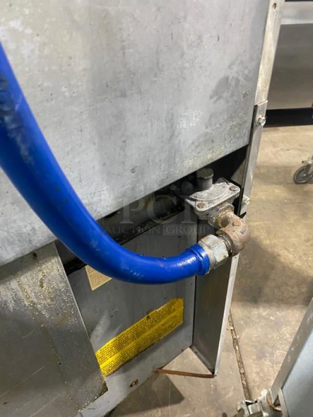 U.S. Range stainless steel 10-burner range/double oven combo with backsplash, overhead salamander shelf, casters, and wired racks.