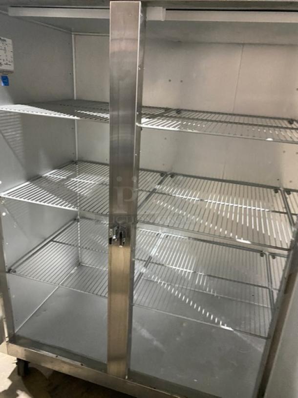 Traulsen stainless steel triple door reach-in freezer, Model G31010, with poly coated wire racks on casters, in good condition.