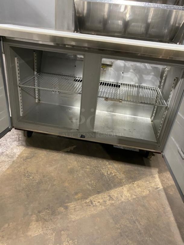 Randell stainless steel 2-door refrigerated prep table, model 9303-7, with double overhead shelf, wired racks, on casters.