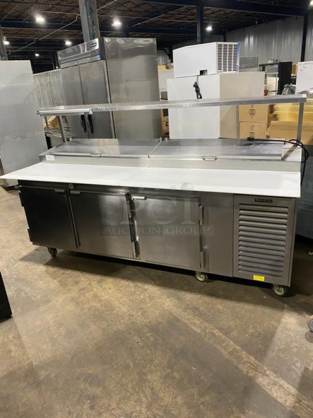 Traulsen stainless steel 3-door refrigerated pizza prep table with cutting board, overhead shelf, poly-coated racks, model TRP096S.