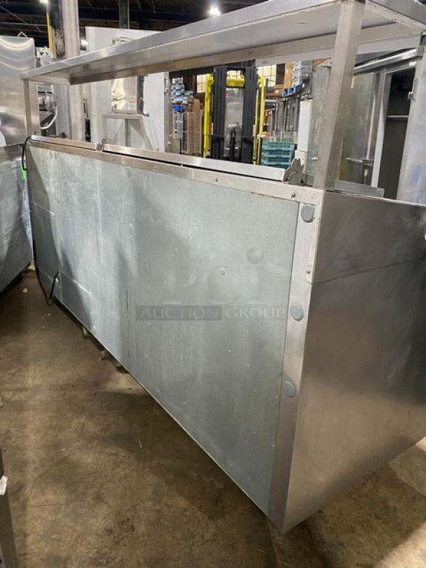 Traulsen TRP096S commercial stainless steel 3-door refrigerated pizza prep table with overhead shelf, cutting board, and poly-coated wire racks, on casters.