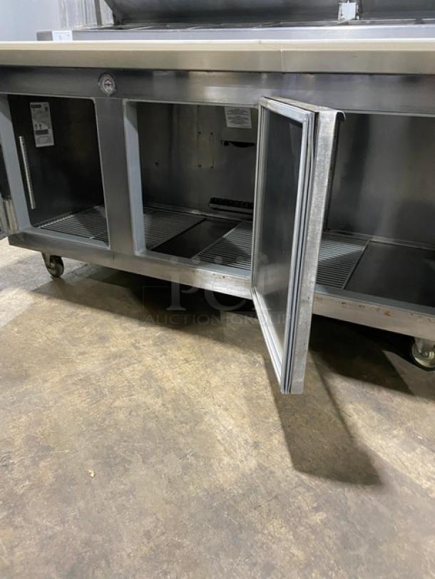 Traulsen TRP096S commercial stainless steel 3-door refrigerated pizza prep table with cutting board, overhead shelf, and poly-coated wire racks. Equipped with casters. Model: TRP096S, SN: T72139G19, 115V.