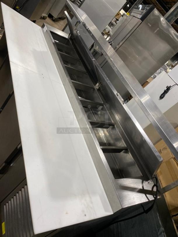 Traulsen TRP096S commercial 3-door stainless steel refrigerated pizza prep table, cutting board, overhead shelf, poly-coated racks, on casters.