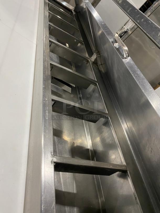 Traulsen stainless steel 3-door refrigerated pizza prep table, model TRP096S, with cutting board, overhead shelf, and casters.