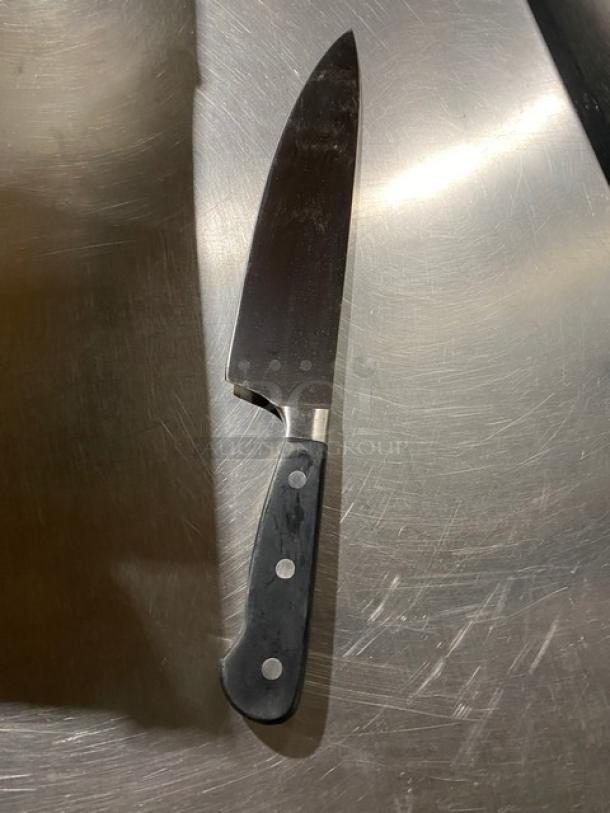 Commercial stainless steel chef knife with a sharp blade and black grip handle, in good condition.