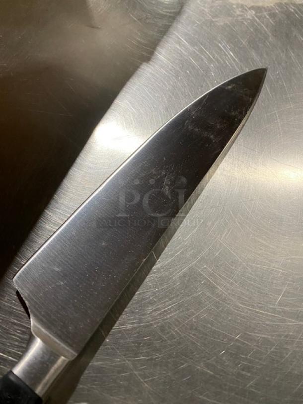 Commercial stainless steel chef knife with black grip handle, shown with a polished blade, in excellent condition.