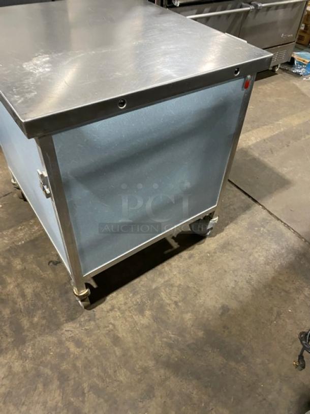 Commercial stainless steel rolling utility table with casters. Features a durable top, side panels, and lockable wheels.