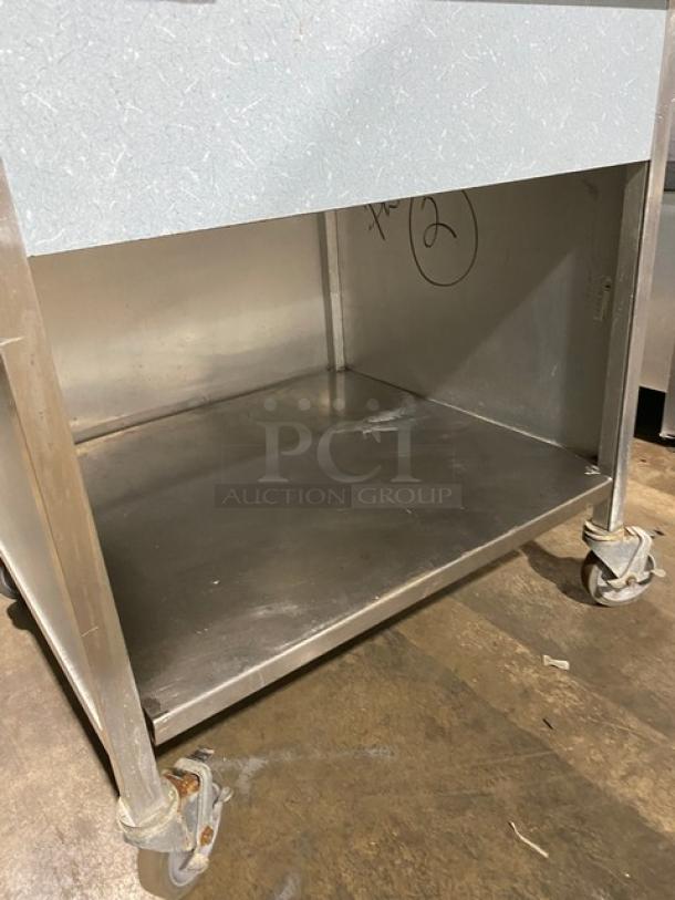 Commercial stainless steel rolling kitchen utility table with casters, durable, under-shelf storage, slight wear.