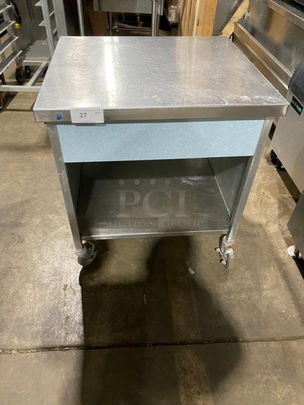 Commercial stainless steel rolling kitchen utility table on casters, with storage shelf, in good condition.
