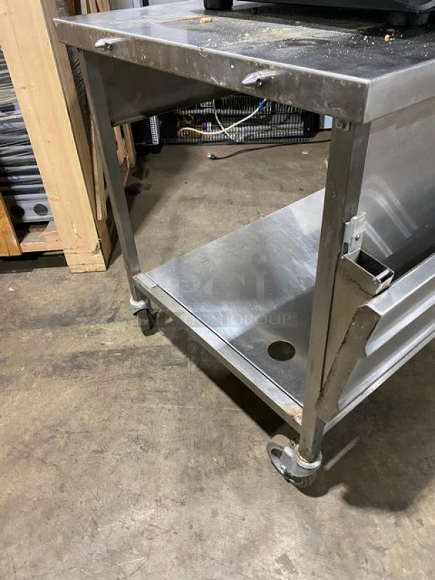 Commercial stainless steel table on wheels, featuring an open shelf and sturdy construction. Good condition, ideal for kitchen use.