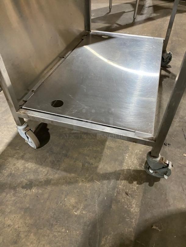 Commercial stainless steel cart with two tiers and smooth finish, featuring caster wheels for mobility. Used condition.