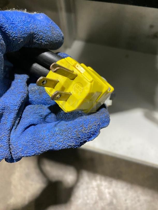 Yellow power plug for Servolift Commercial Refrigerated Cold Well, Model 503-1R, 120V, shown with blue glove for handling.