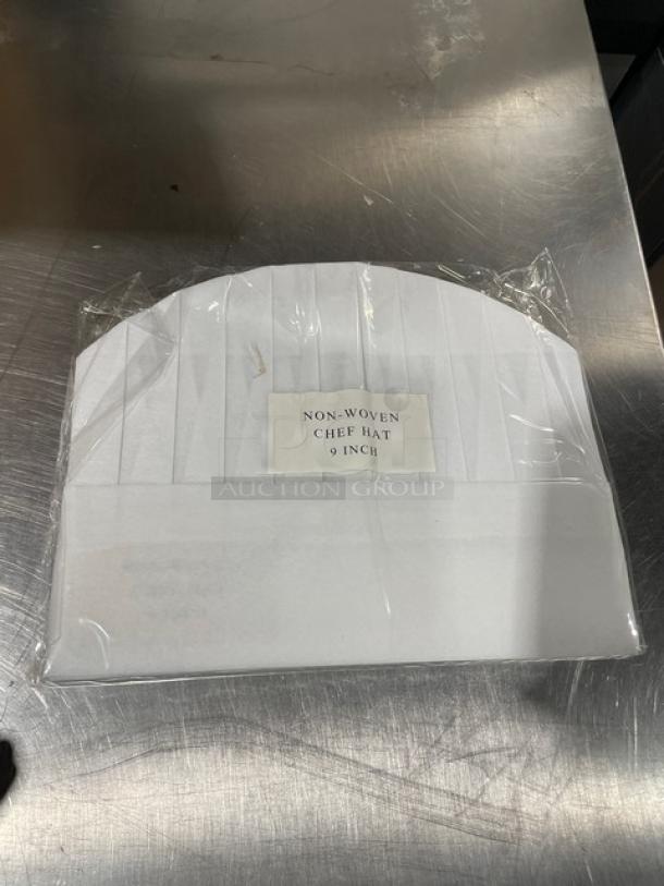 New Landau Uniforms white non-woven 9" round chef hat in packaging. Label reads "Non-Woven Chef Hat 9 Inch."