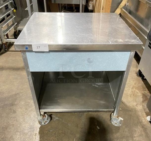 Stainless steel rolling kitchen utility table with casters and lower shelf; used condition, label reads "Lot 27".