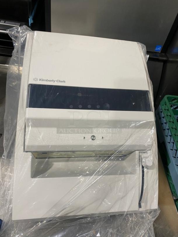 Kimberly-Clark white roll towel dispenser, model 0971700, new condition, protective plastic cover, wall-mounted design.