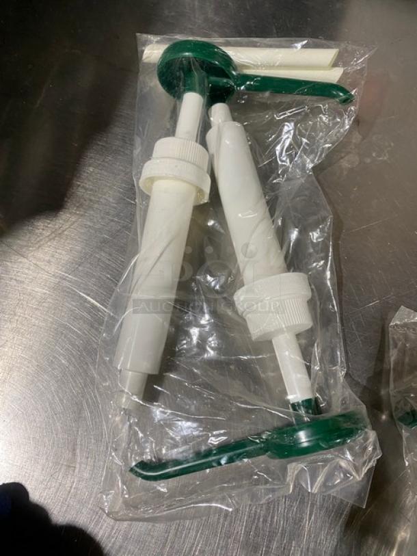 New commercial condiment dispenser pump set, white with green handles, in original packaging.