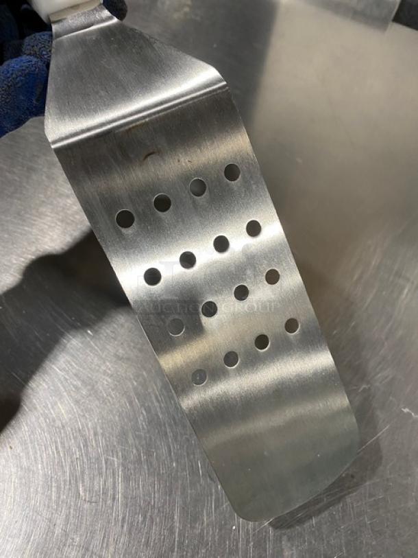 New commercial stainless steel perforated flex turner, model PFT-10P, with white grip handle. Ideal for kitchen use.