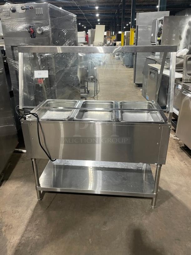 Serv-Ware stainless steel hot food table, model EST3-1, with 3 wells, sneeze guard, 120V power, on legs, in used condition.