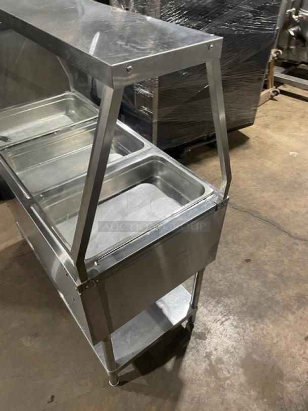 Serv-Ware stainless steel hot food table, model EST3-1, with 3 open wells, sneeze guard, on legs, 120V, SN: M1100228.