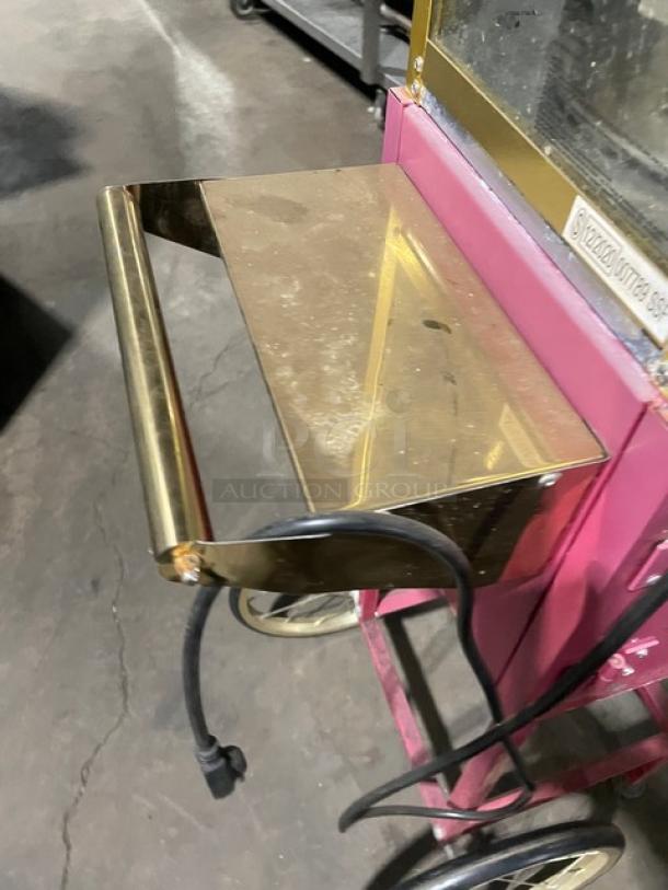 Great Northern Popcorn pink commercial popcorn machine on casters, features electric power, brass tray, visible wear.