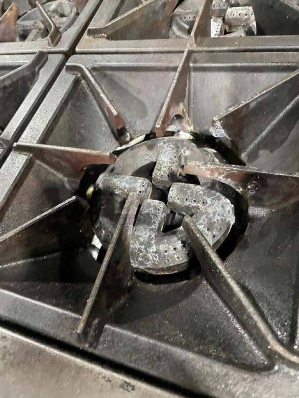 Cooper Beech natural gas 4-burner range close-up, showing robust metal grates. Suitable for commercial kitchens.