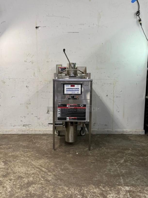 Wells KFC pressure fryer, stainless steel, with control panel, used condition, safety instructions visible, on wheels for mobility.