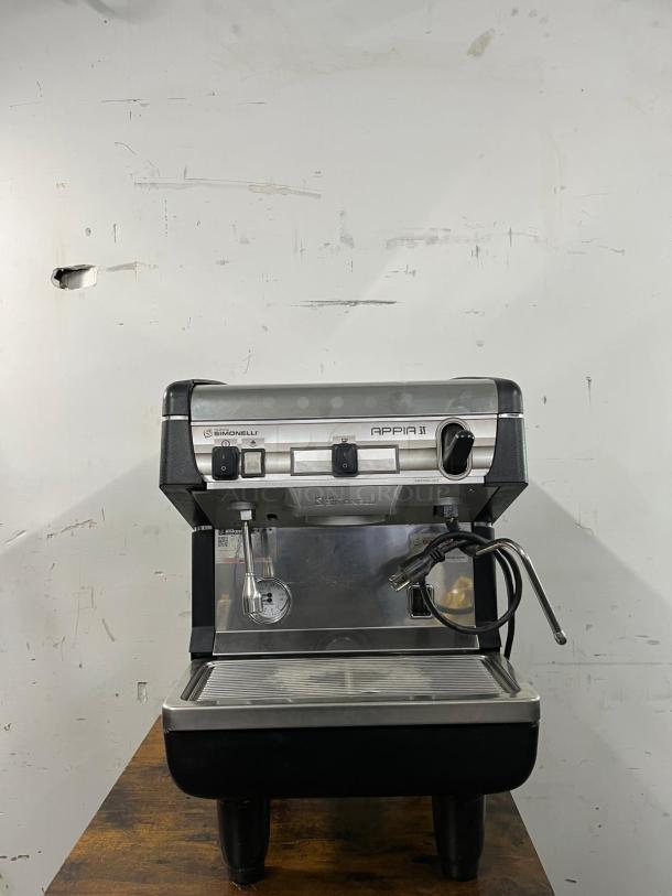 Nuova Simonelli Appia II espresso machine, commercial-grade, stainless steel, reliable, visible power cord, good condition.