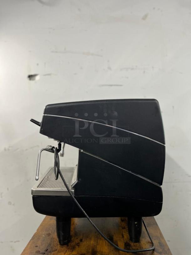 Nuova Simonelli Appia II espresso machine, commercial-grade, side view, black casing, visible steam wand, good condition.