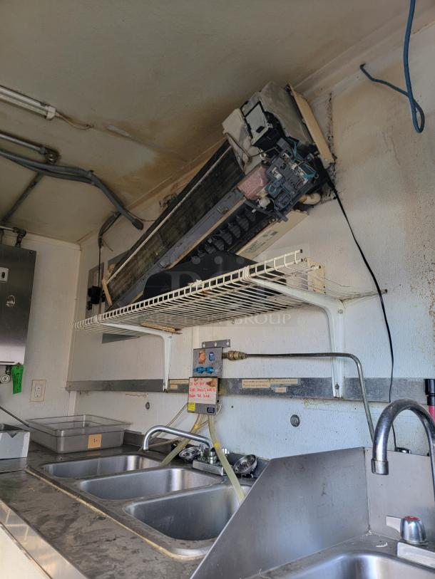 2020 16' Diamond Cargo food trailer interior with triple sink, shelf, and Mitsubishi A/C unit. Turnkey kitchen setup.