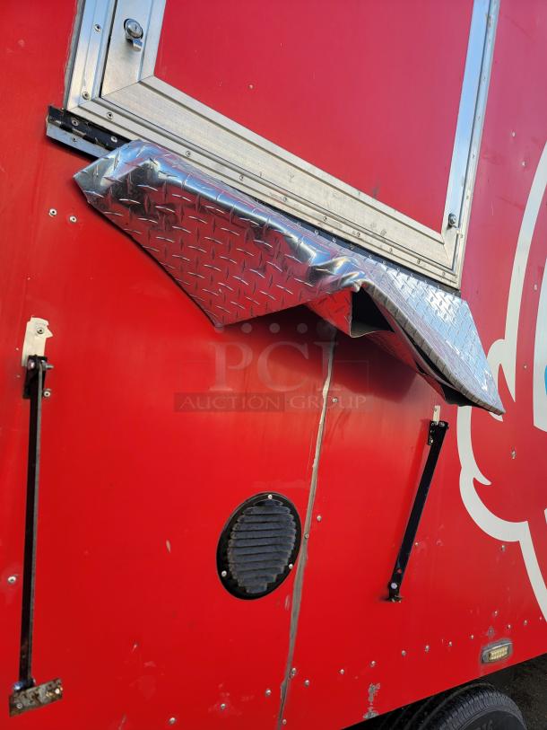 Red Texino food trailer with a diamond-plate service window cover. Visible ventilation and support brackets on exterior.