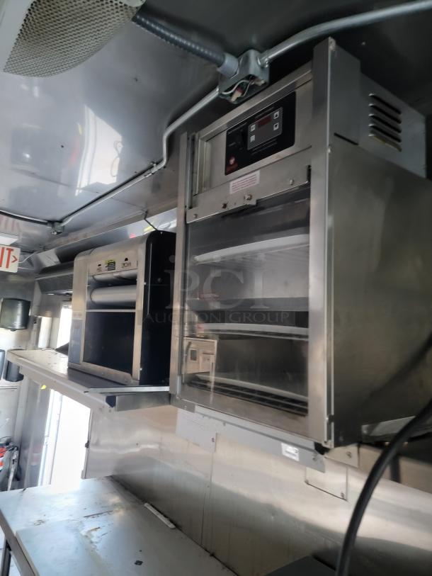 Interior of 2021 Texino Food Trailer showcasing premium heavy-duty cooking equipment, including a CaptiveAire exhaust hood and refrigeration units.