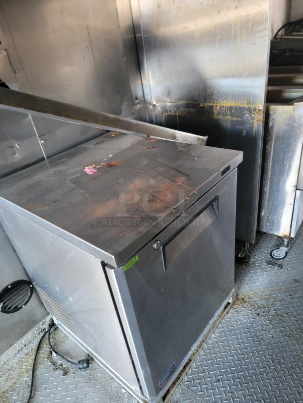 2021 28' Texino Food Trailer interior with stainless steel refrigeration unit, heavy-duty exhaust hood, and cooking equipment.