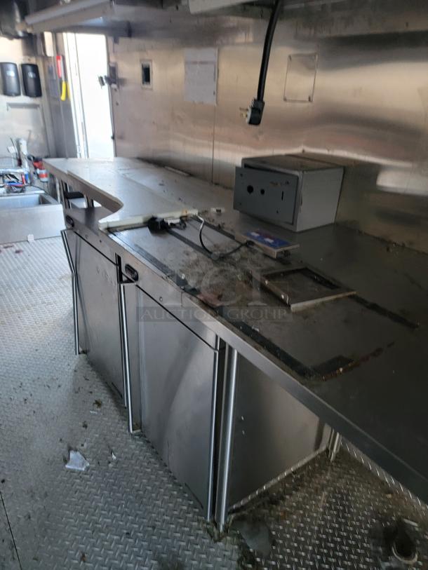 2021 28' Texino Food Trailer interior, featuring stainless steel counters, heavy-duty exhaust hood, and utility panel, ideal for mobile cooking.