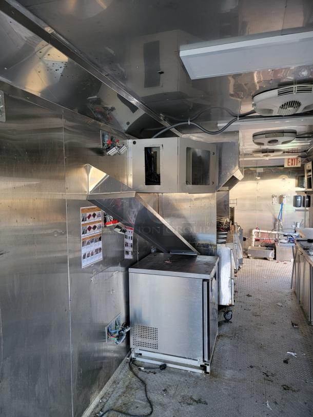Interior of 2021 Texino 28' Food Trailer, featuring a CaptiveAire hood, Turbo Air refrigeration, and commercial cooking appliances.