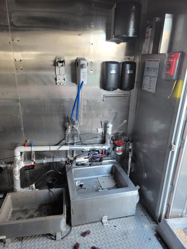Interior of 2021 Texino Food Trailer showing stainless steel walls, plumbing setup, and commercial sink. Ideal for mobile kitchen.