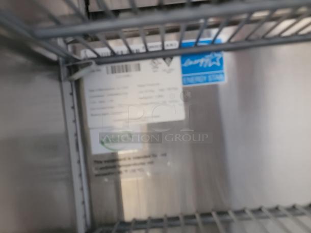 Blurred interior view of a Hoshizaki commercial refrigeration unit's shelf, showing an NSF certification label and R-600a marking.