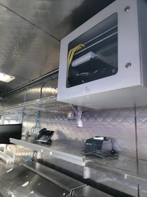 Professional-grade 24' food trailer interior with stainless steel surfaces, phone, and equipment. Ready for high-volume service.