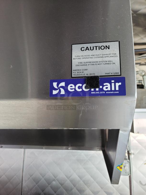 Stainless steel interior of a 24' Quality food trailer with caution and eco-air labels visible.