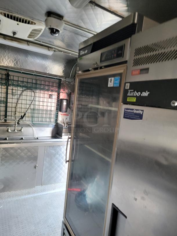 24' Quality food trailer interior with stainless steel finish, Turbo Air fridge, dual sink, and NSF-certified equipment.