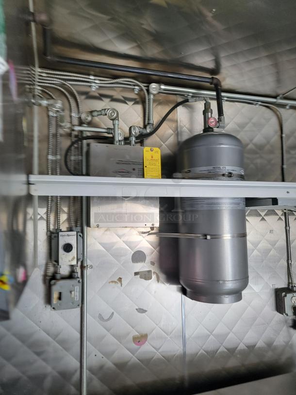 Interior view of a Quality 24' food trailer showing stainless steel construction, plumbing, and electrical wiring.